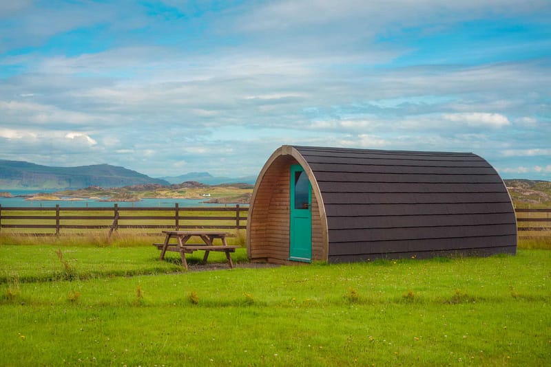 A proposed small cabin in a grassy field with a picnic table for glamping pods.
