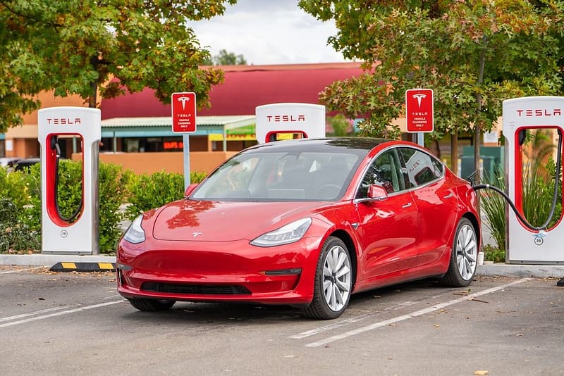 A red tesla model 3 parked at a charging station in California.