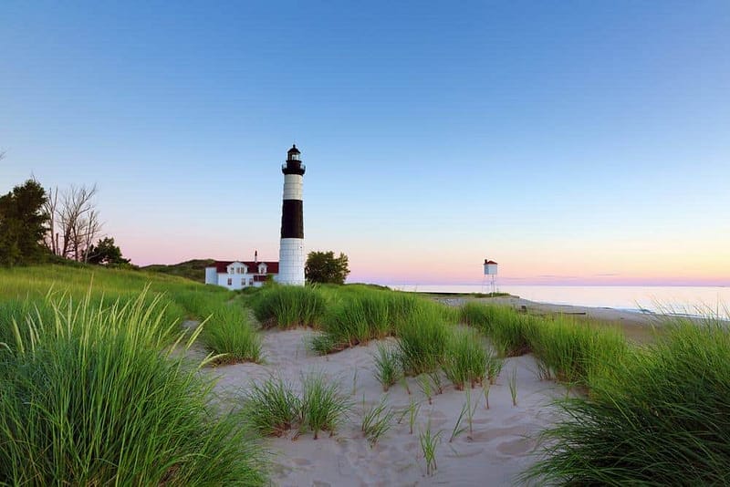A sand dune with a lighthouse in the background.