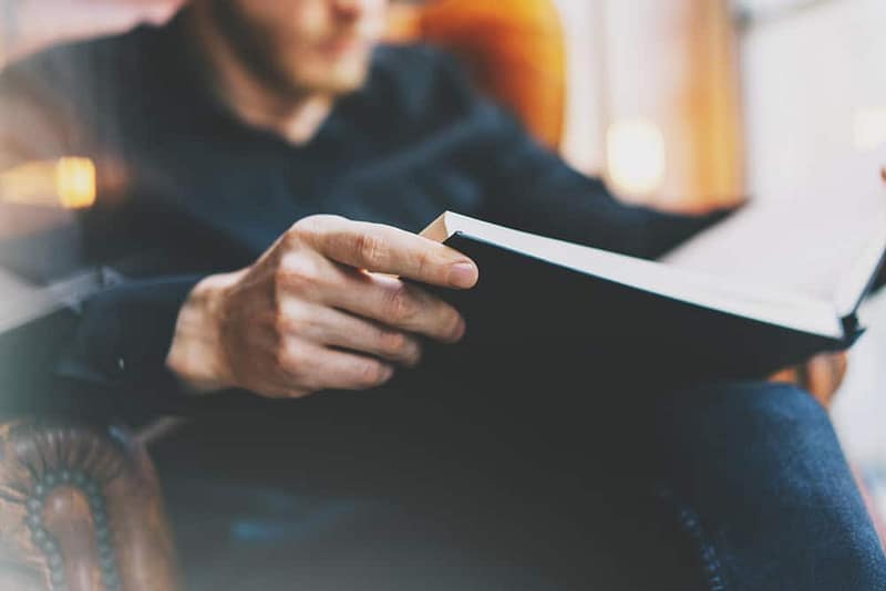 A man is sitting in a chair reading a book.
