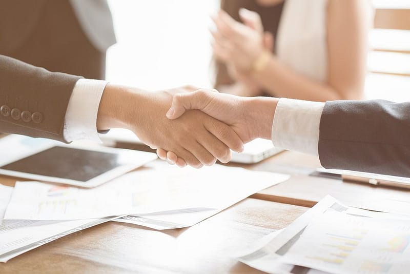 Two business people shaking hands over a table during an acquisition deal at a RV dealership.