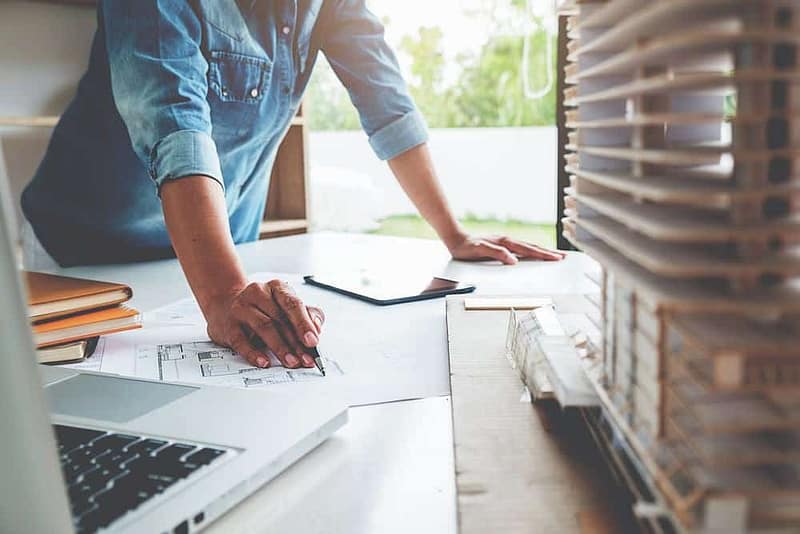 A woman working at a desk with a laptop and blueprints in a 33.4-Acre Luxury RV Resort.