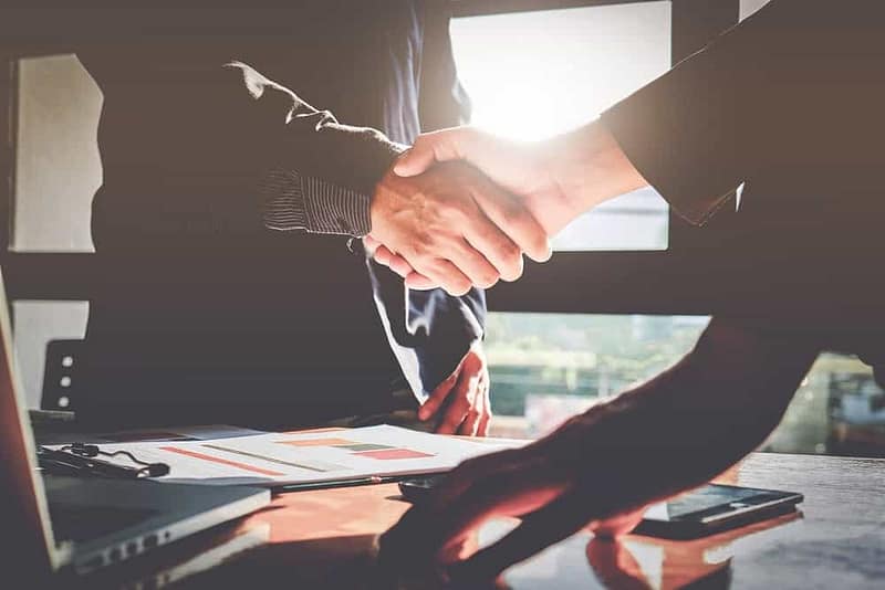 Two business people from Forrest Street Partners shaking hands in front of a desk, as the company expands its portfolio by investing in an MH community.