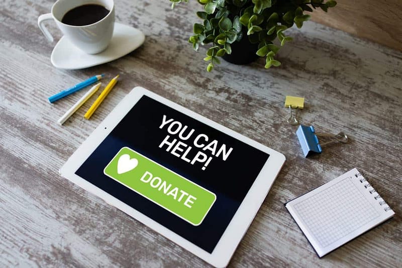 A tablet with the words you can help on it sitting next to a cup of coffee.