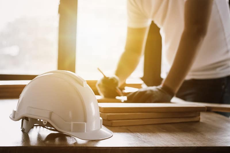 A construction worker wearing a hard hat on a wooden table.