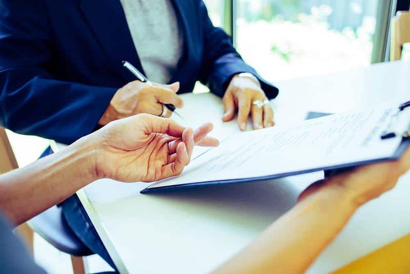A person signing a document at a table.