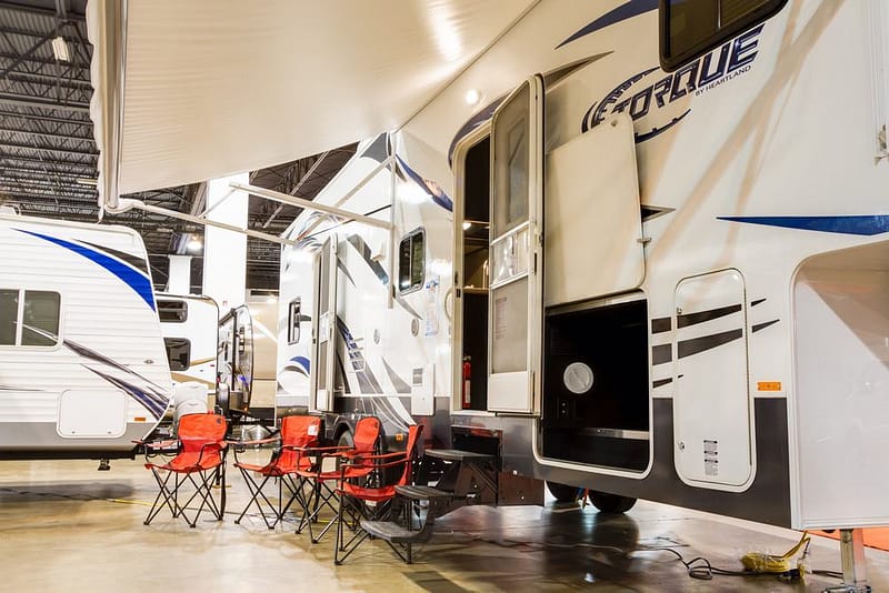 Two rvs in a showroom with chairs and tables.