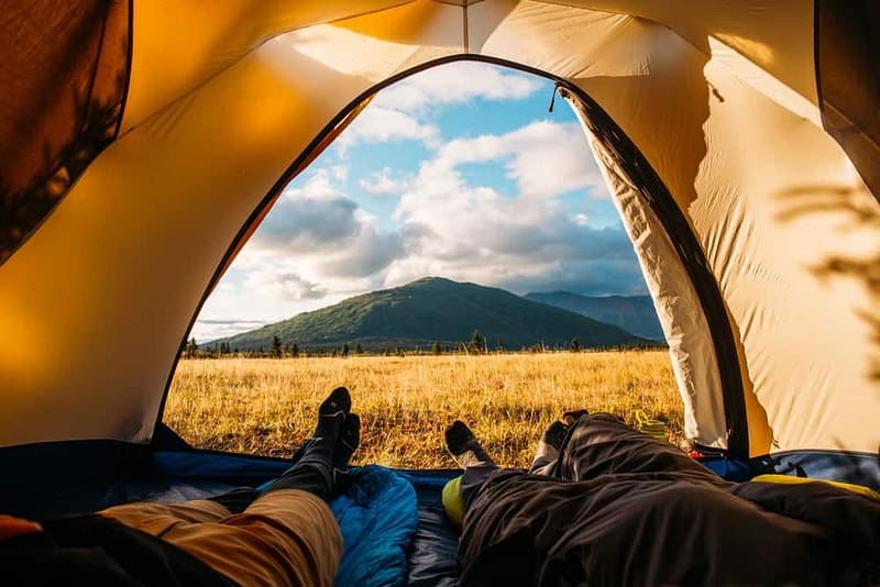 Two annual campers sleeping in a tent with mountains in the Canadian background.