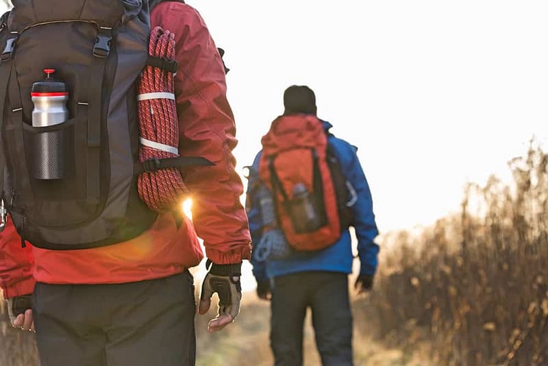 Two campers walking down a trail with backpacks.