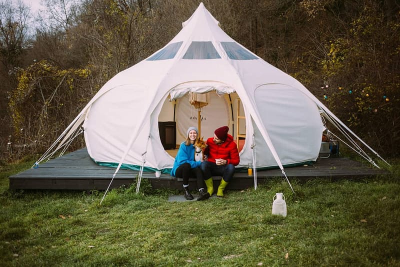 Two women sitting in front of a Glamping Blossoms yurt tent with an AceVolt portable power station.