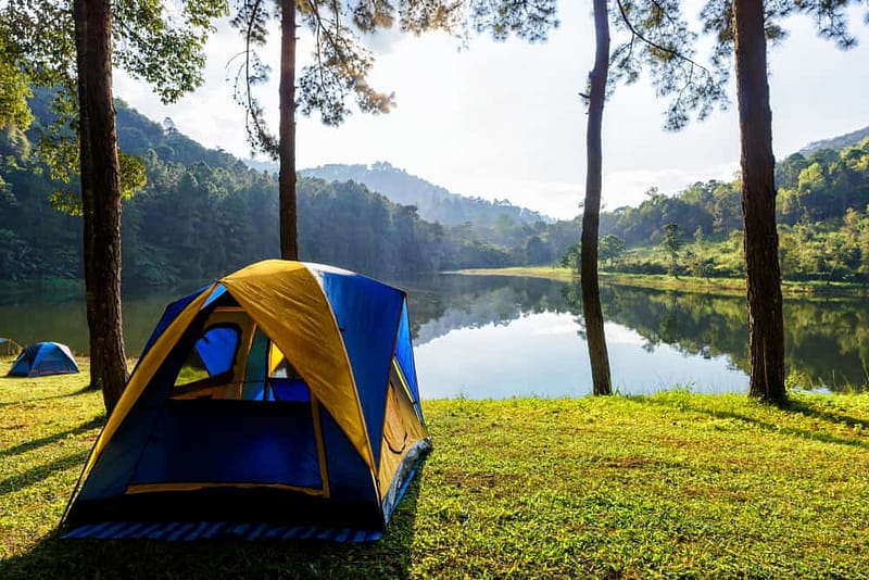 One of the best places to camp in the US region is a tent set up on the grass near a lake. This picturesque spot offers breathtaking views and tranquility, making it a perfect choice