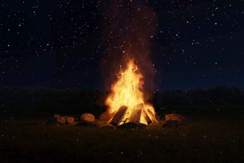 A bonfire in a field at night with stars in the sky, on Lands Managed by Arcata Field Office.