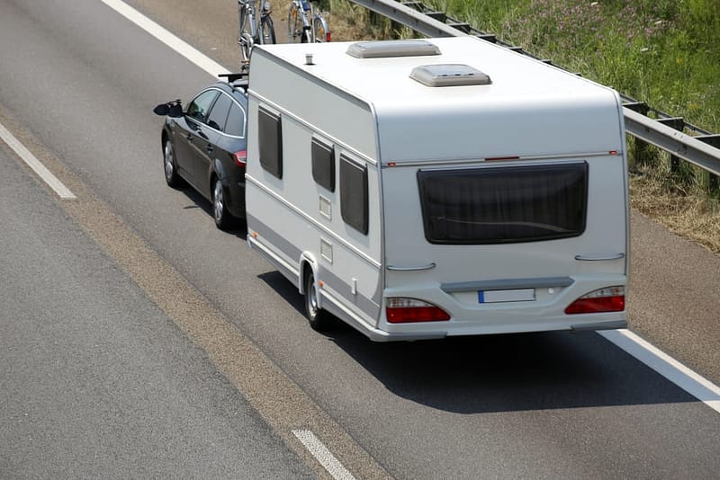 A truck-friendly RV on the side of the road with a car behind it, providing towing education and training.