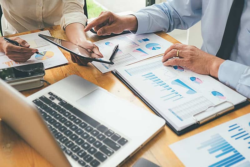 The Rapido Group, in collaboration with FCA Bank, engaging in a Pan-European Partnership, involving business people analyzing graphs on a table.