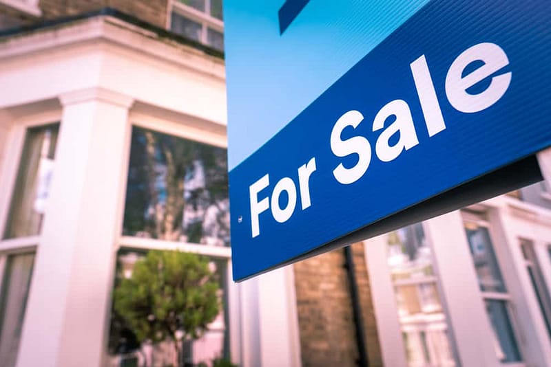 A for sale sign in front of a house listed for sale.