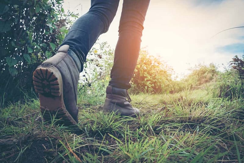 A person walking on a trail in a pair of hiking boots, braving severe rainfall.