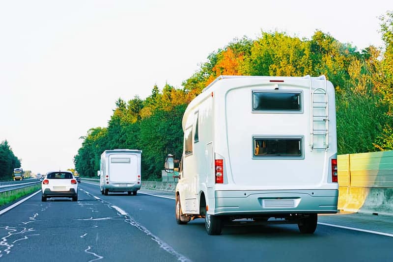 Two RVs on a highway, utilizing a mobile app for their travel planning.