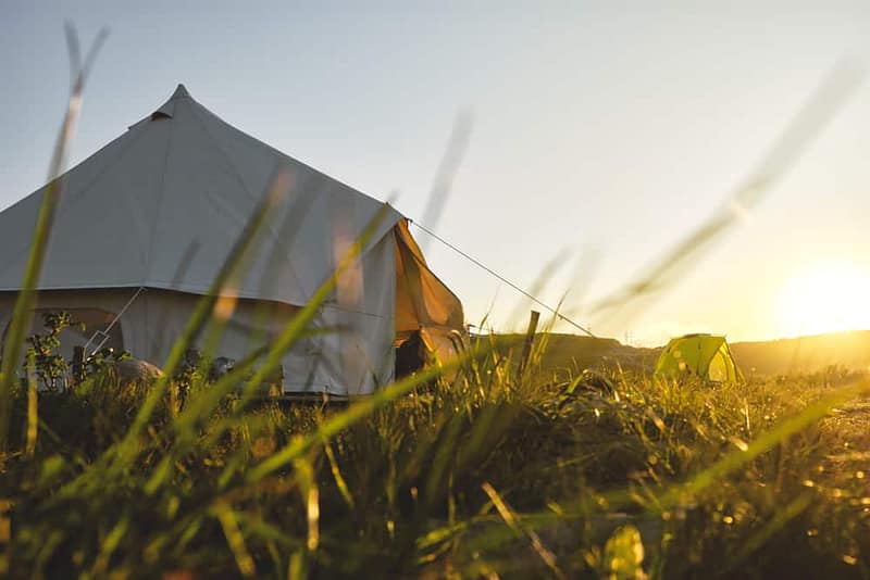 A glamping tent in the grass with the sun setting behind it in Texas.