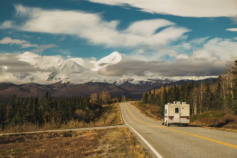 RVers enjoying the picturesque views of mountains as they travel down a road, referencing the RVshare quarterly guide.