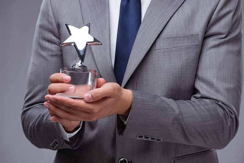 A businessman proudly displaying the 2023 COHCE Award trophy, having met all the criteria for this prestigious accolade.