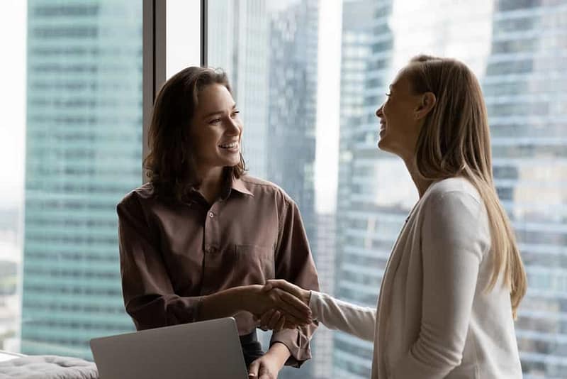 Two RV Women's Alliance members shaking hands in front of a window as the organization expands into Canada.