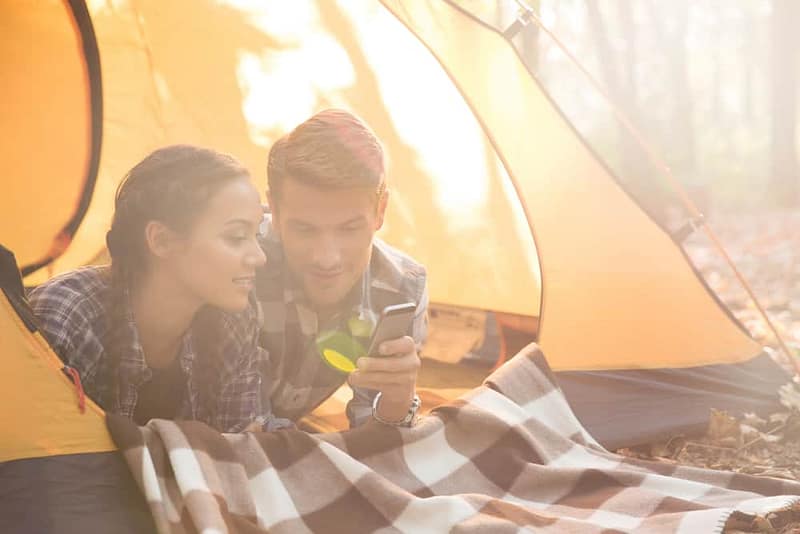 Campers in a tent using their phone.
