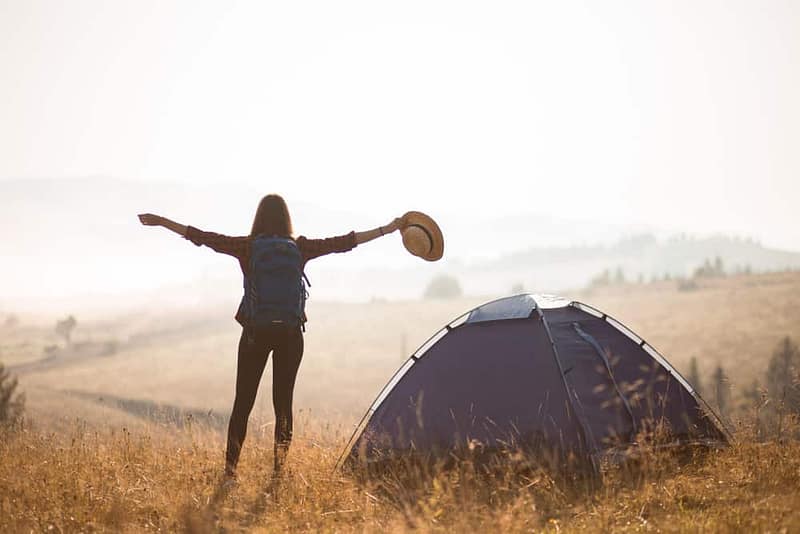 A woman expands her reach with arms outstretched in a field.