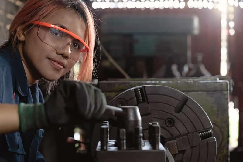 A woman, certified professional, wearing glasses is working on a machine.
