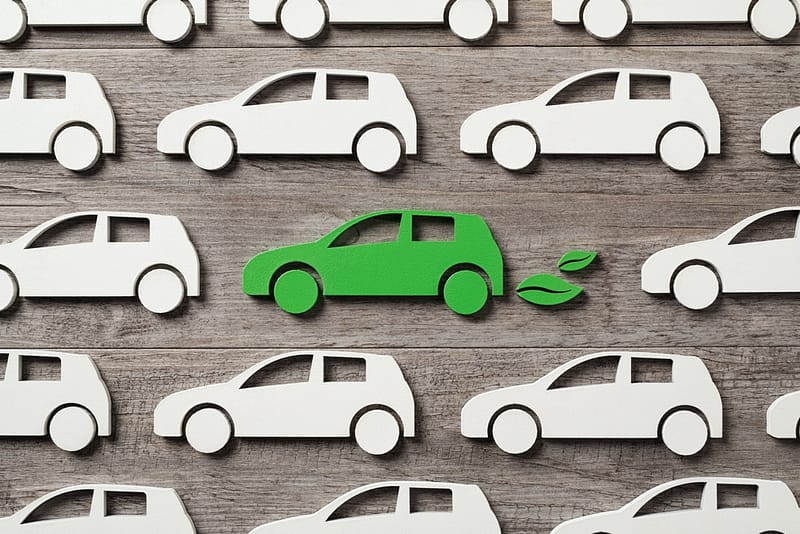 A group of green paper Campervan cars on a wooden background.