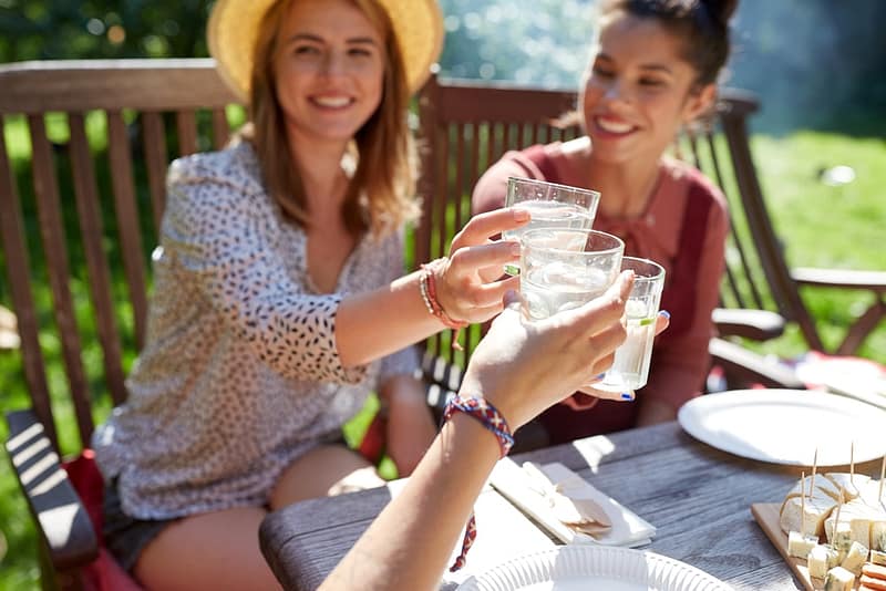 Two women toasting with water glasses at a picnic table at the first GCC-based property of Experiential Hospitality Group's Earth Hotels.