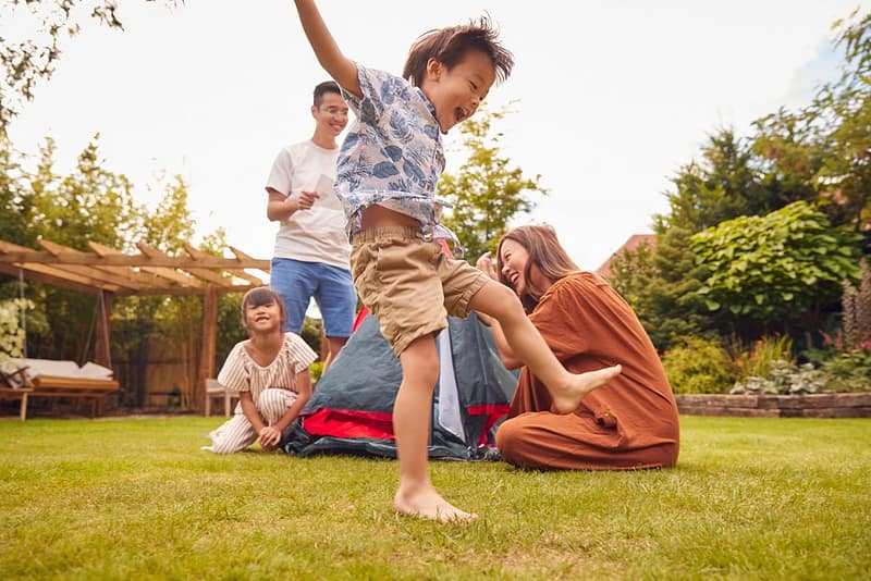 A family is enjoying outdoor activities in the backyard with a tent.