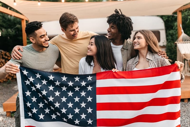 A group of friends holding an American flag during Memorial Day Weekend.