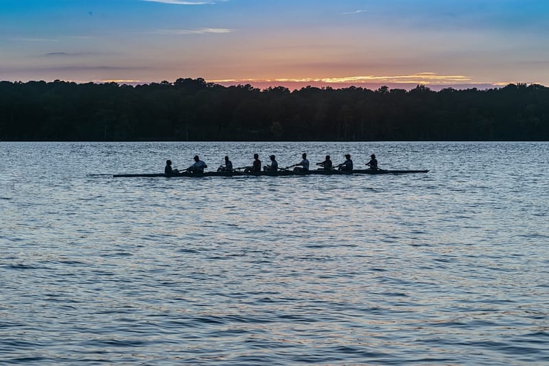 A group of rowers on a lake at sunset, enjoying the tranquil Timberline scenery.