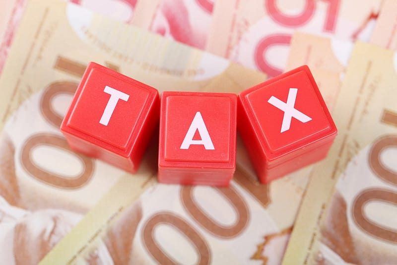 A red block with the word tax on top of a stack of Canadian dollars, aimed at private campground owners in Canada who can benefit from the small business deduction.