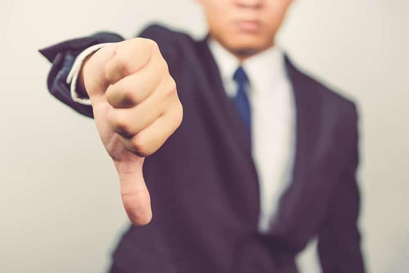 A man in a suit is opposing glamping by giving a thumbs down sign.