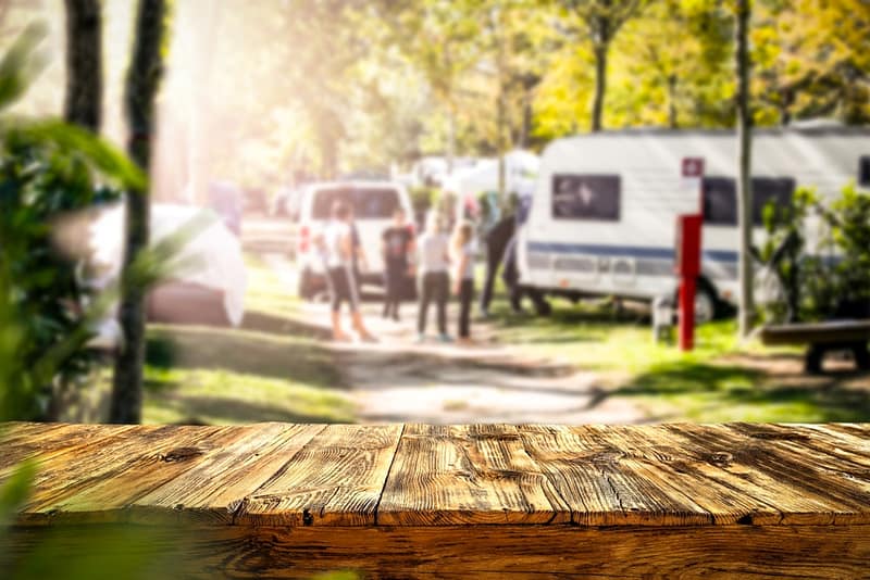 A wooden table in a park with Kampgrounds of America (KOA) RVs in the background.