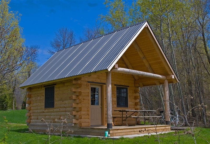 A small log cabin with a metal roof located in Vermont Campgrounds.