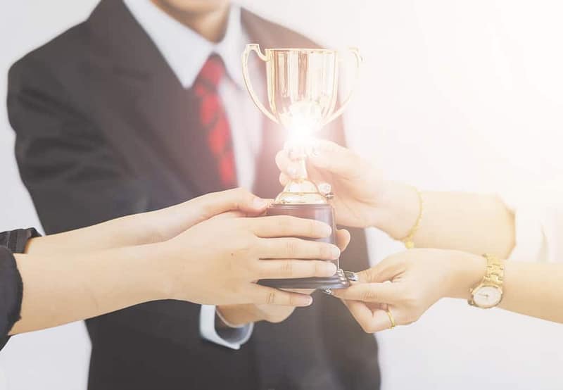 A group of business people holding up a COHCE Award trophy.
