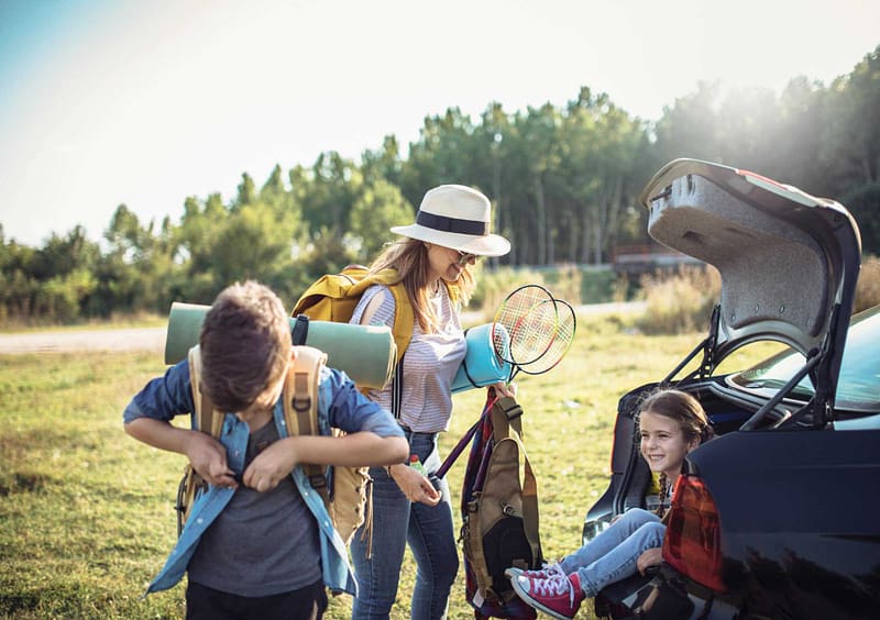 A woman and her children are opening the trunk of a car to begin their camping adventure at Kentucky Park.