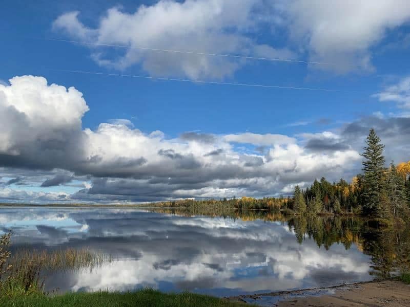 A serene lake with clouds reflected in it, perfect for those anticipating a busy summer at Northern Ontario campgrounds.