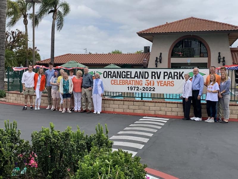 President of CampCalNOW standing in front of sign for Orangeland RV Park.