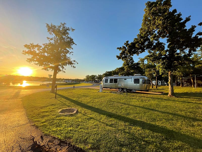 A TACO airstream parked in a grassy area near a lake, perfect for camping in Texas.
