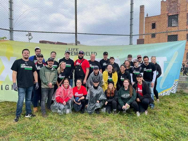 A group of people from Life Remodeled posing in front of a banner for Community Revitalization.