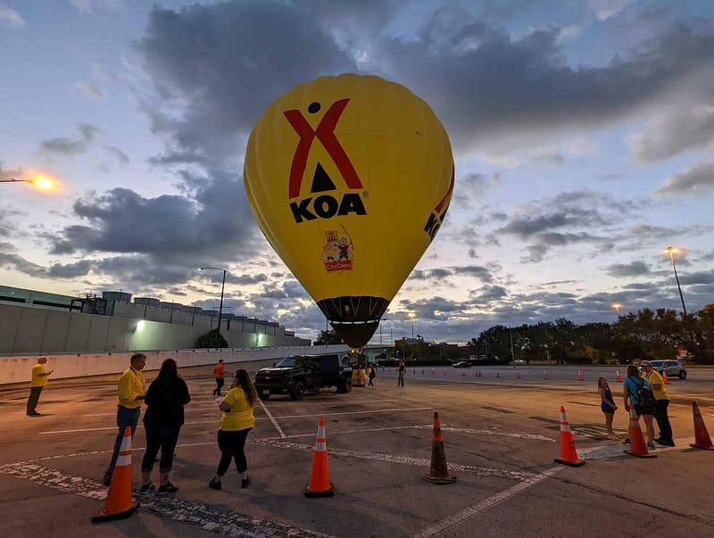 A hot air balloon flies over a parking lot at dusk during the 2022 KOA Convention in Orlando, creating a stunning sight for attendees of the Expo.