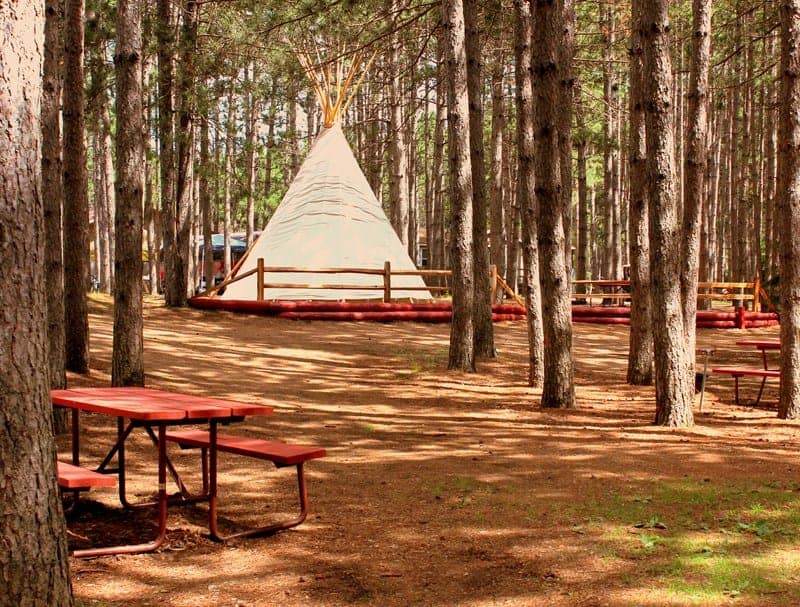 A teepee sits in the middle of a wooded area at Chautauqua Lake KOA Holiday.