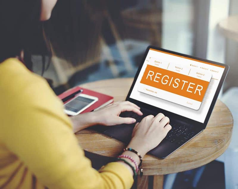 A woman using a laptop with the word register on it.