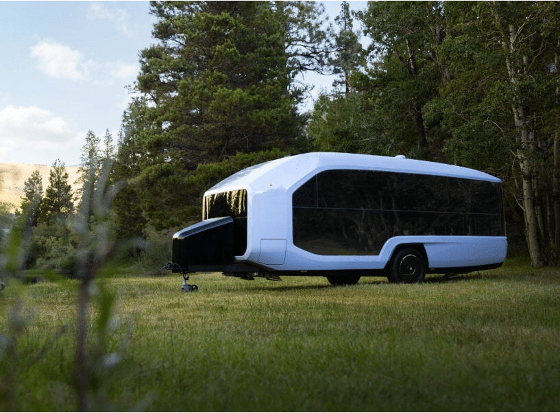 An Electric Travel Trailer parked in a grassy field.