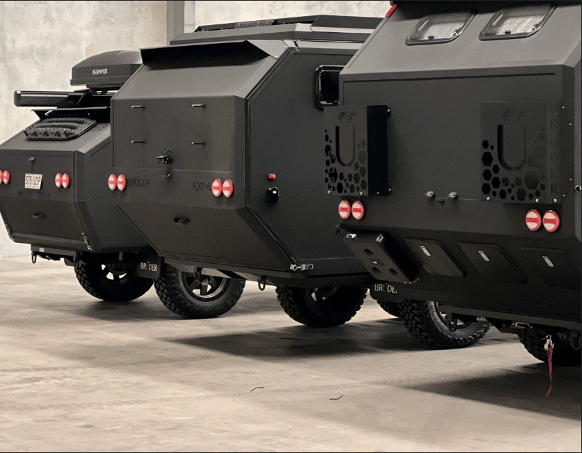 A group of black vehicles parked in a warehouse, showcasing the innovative creations of Global Off-Road Trailer Innovators.