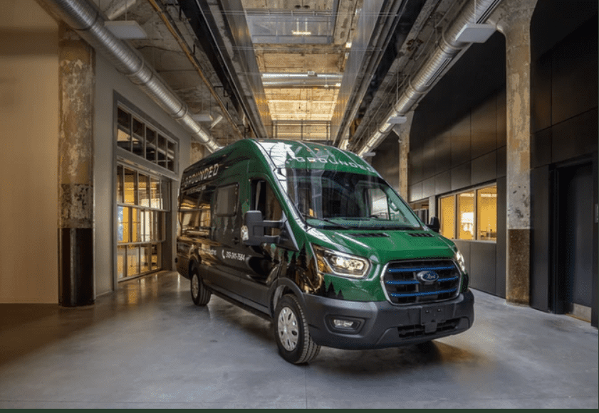 A green ford transit van is parked inside a Fully Customizable building.
