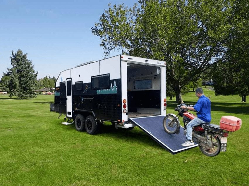 A man riding the Ecocampor motorcycle alongside an Off-Road RV Model camper trailer, creating the perfect Outdoor Experience.